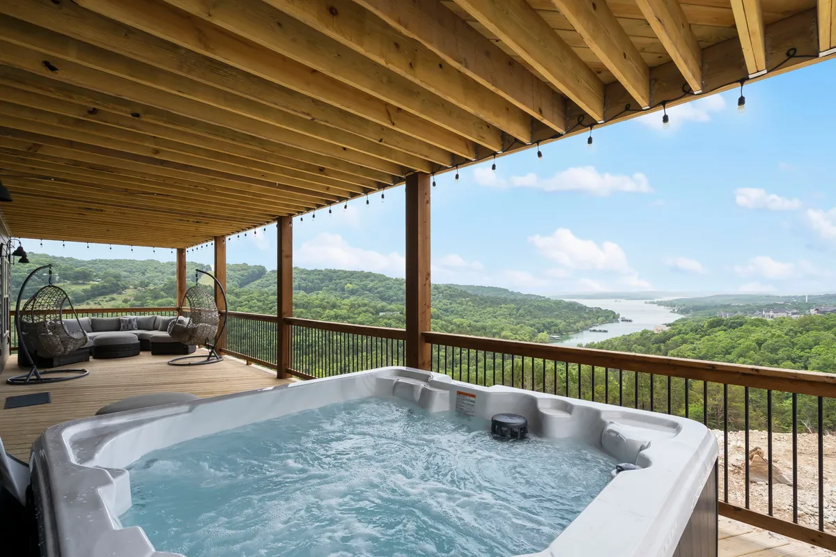 An inviting lower deck area featuring a bubbling hot tub and a seating area that overlooks a scenic, tranquil view. This outdoor extension of the fun zone provides a place for relaxation after indoor activities.