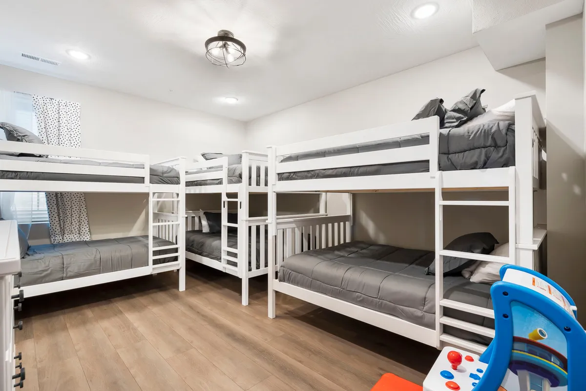 A playful and cozy bunk room with wooden flooring, sturdy bunk beds, and a child's toy on the floor. The atmosphere is warm and inviting, perfect for children to play, read, or share bedtime stories.