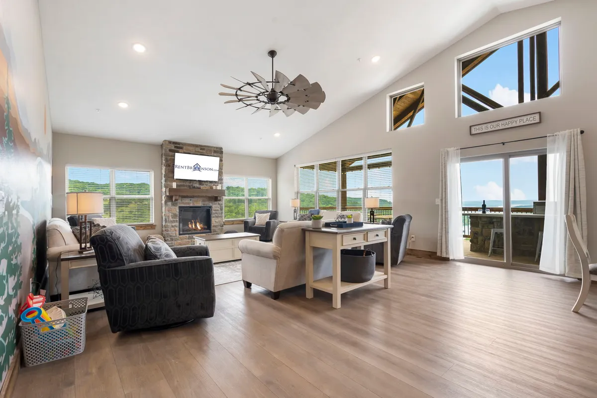 A cozy open-concept space that combines a seating area with a stone fireplace, large windows with views, and a spacious dining table. The arrangement encourages socializing and creates an inviting atmosphere ideal for family gatherings.