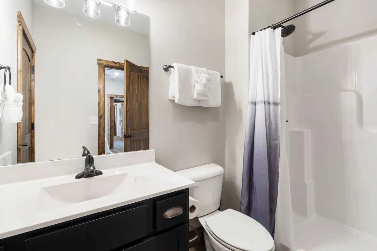A modern bathroom featuring a spacious vanity with a sink, a large mirror, a glass-enclosed shower area, and a toilet. The setting is bright, clean, and serene, emphasizing comfort and convenience.