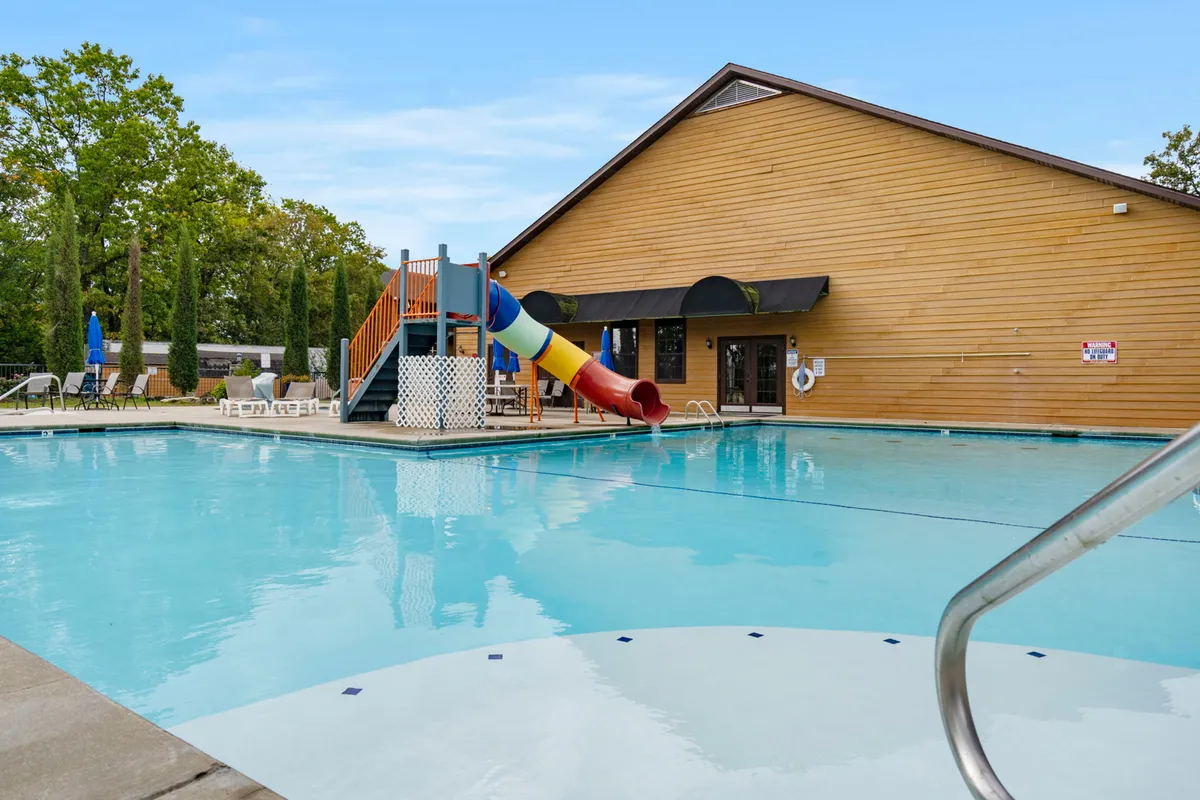 This exterior image showcases a vibrant swimming pool area with a water slide, lounge chairs, and the resort building in the background. The area is lively and playful, making it ideal for family outings and social gatherings.