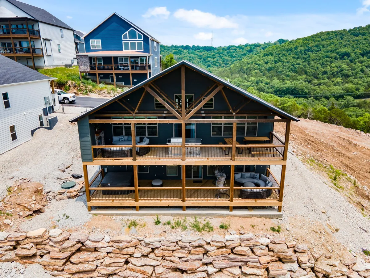 A spacious lake-view property with large wooden balconies surrounded by lush greenery. The scene highlights peaceful outdoor relaxation and scenic views, perfect for returning to after a day of exploring downtown Branson.