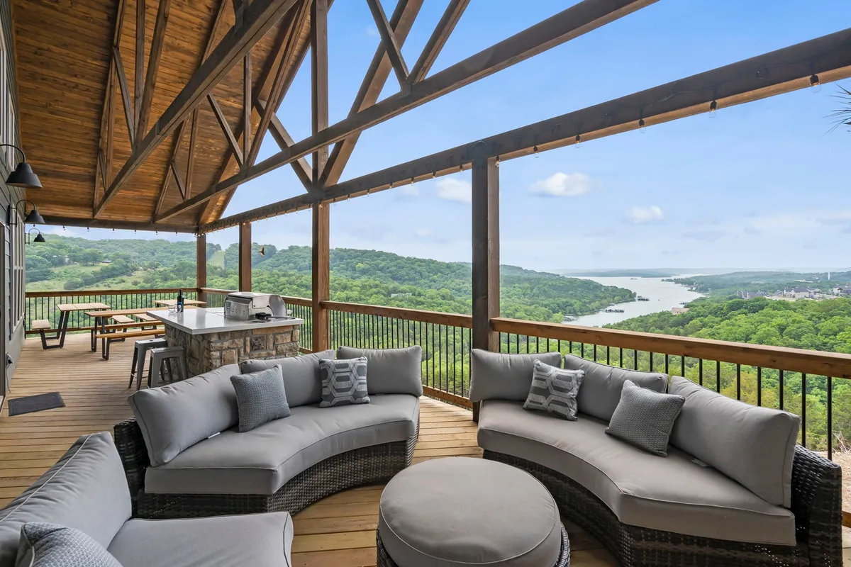 An expansive outdoor area with a curved sectional sofa and an outdoor dining space, set against a panoramic view of rolling hills. The setup is ideal for gatherings, enjoying meals outdoors, and taking in sunsets.